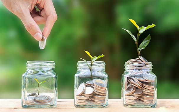 Photo of three glass jars full of change with plants sprouting