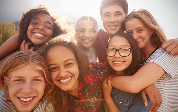 A group picture with seven smiling young people - they are looking at the camera