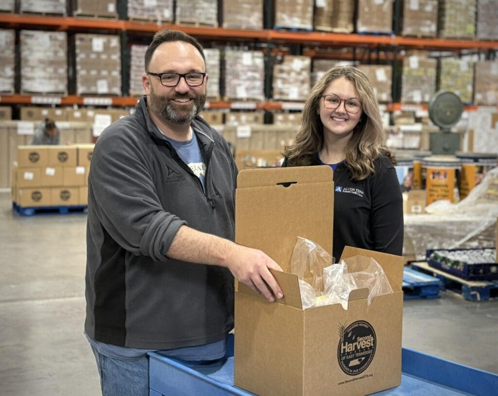 Employees pose with boxes they are filling