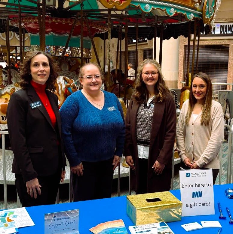 Four ATFCU employees stand behind a table at the job fair. They are smiling and excited to meet with people at the job fair.